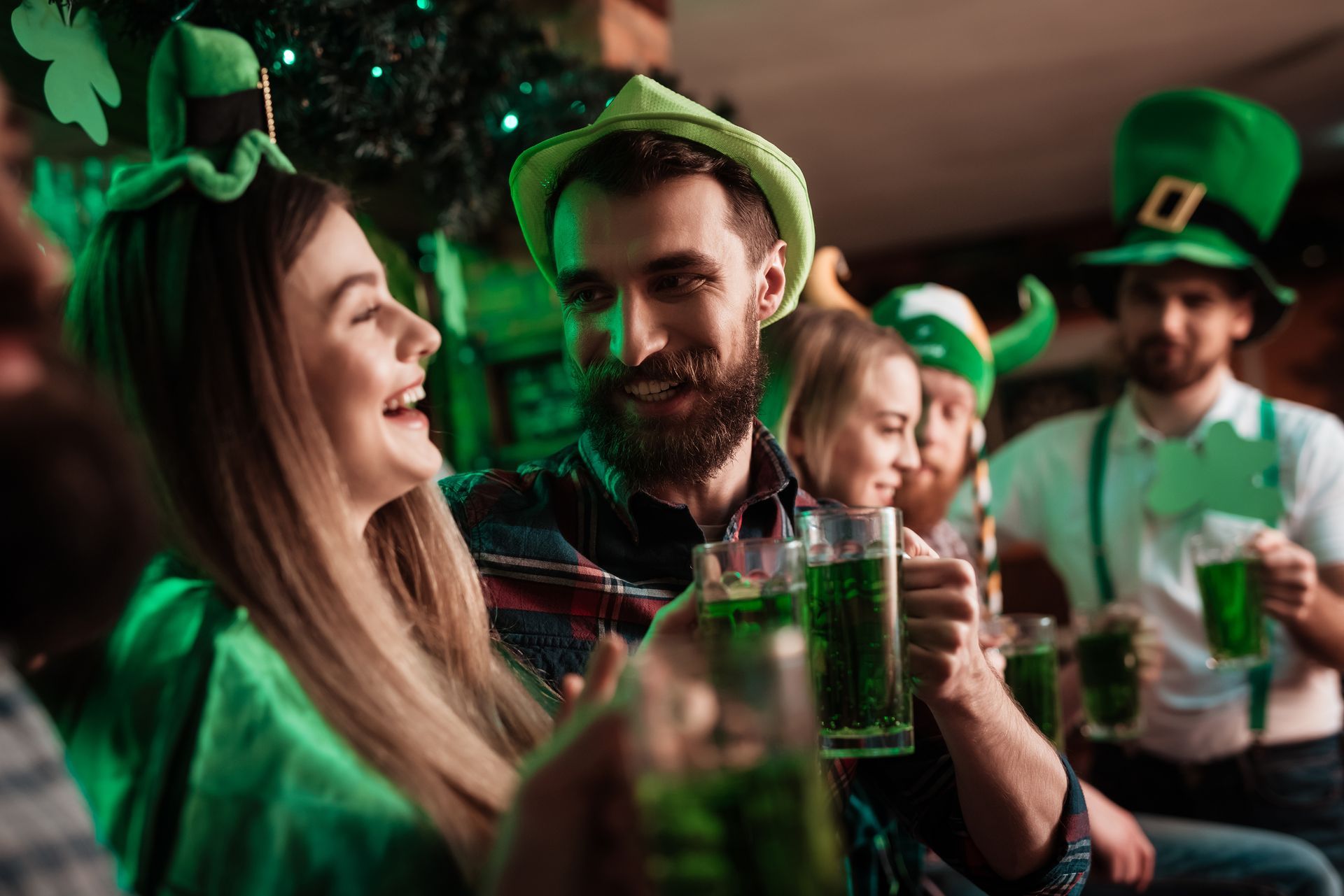 Des personnes coiffées de chapeaux verts partagent des boissons lors d'une fête animée de la Saint-Patrick.