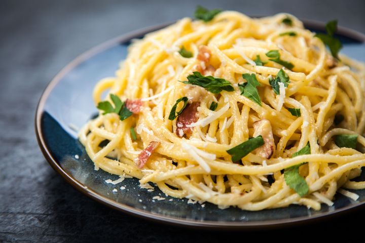 Spaghettis à la carbonara à la pancetta et au persil, servis dans un plat bleu foncé.
