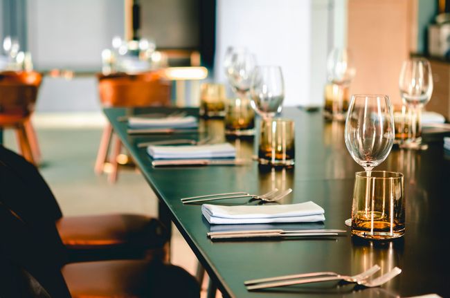 Élégante table de restaurant dressée avec des serviettes noires, des verres à vin et des touches dorées.