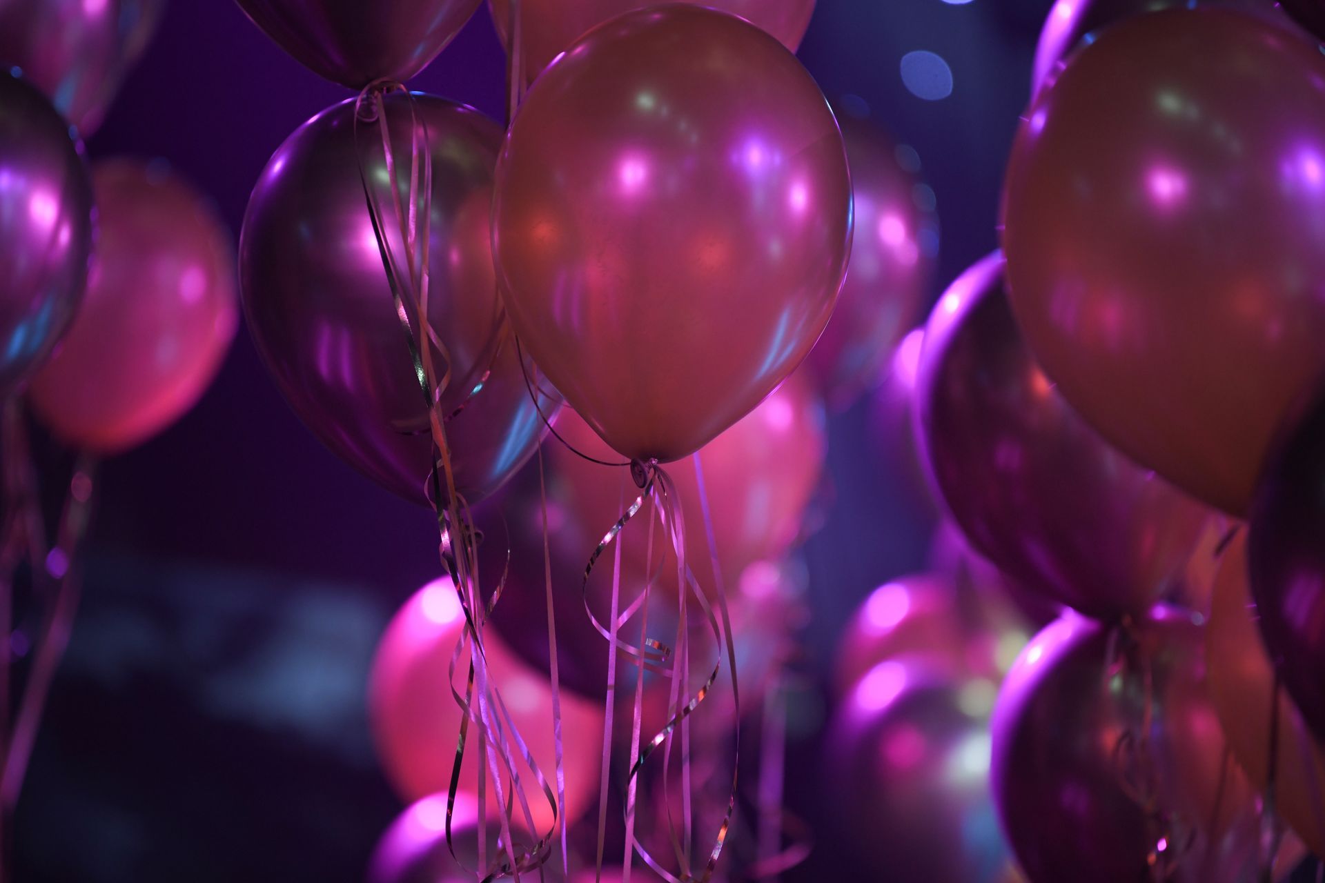 Des ballons violets et roses remplissent une scène de fête doucement éclairée.