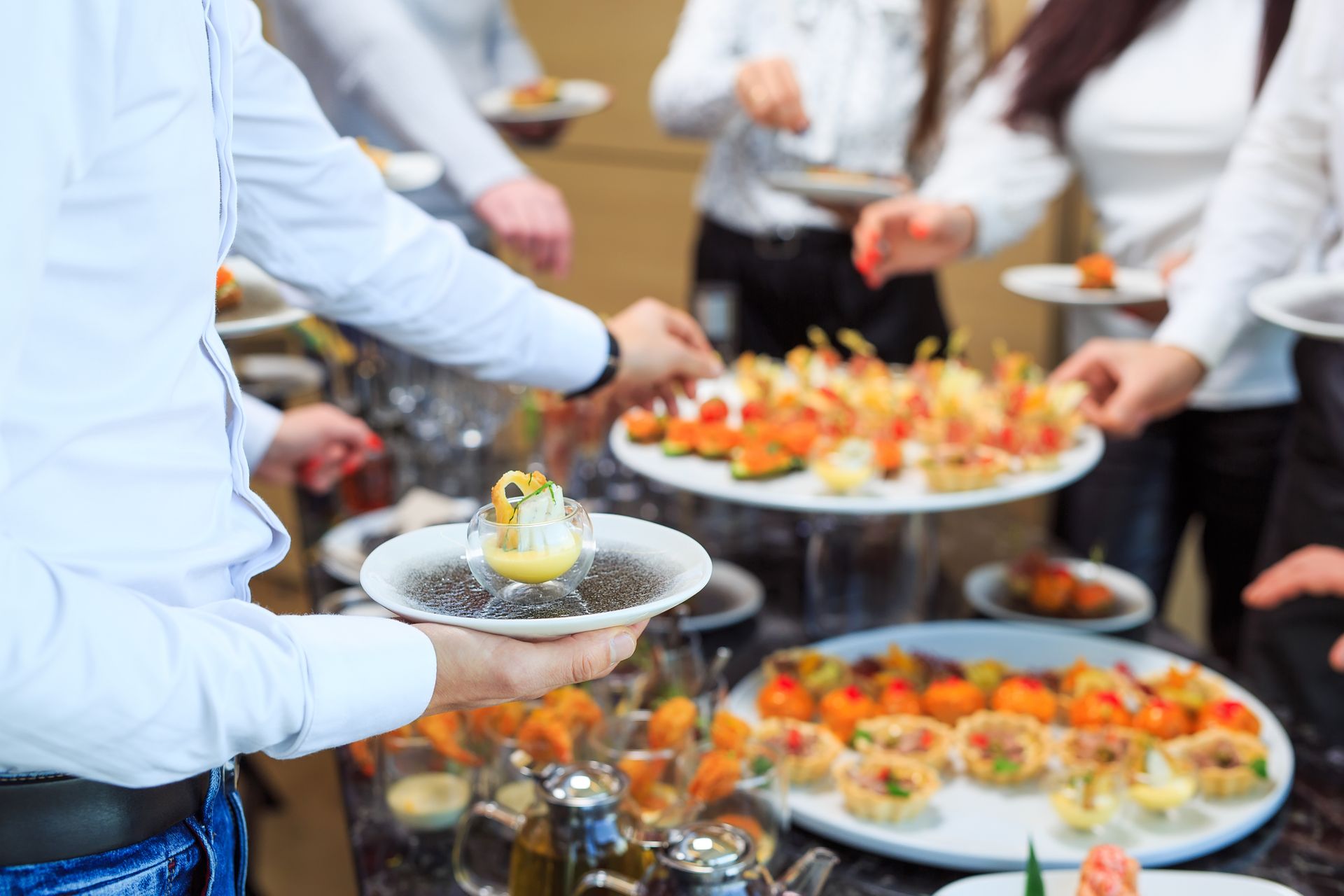 Des personnes servent des amuse-gueules à un buffet lors d'un événement traiteur.