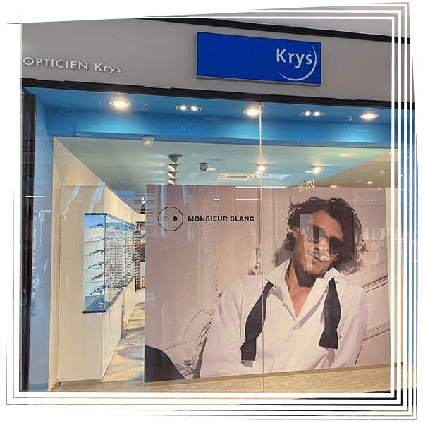 Façade d'opticien avec une enseigne Krys et une publicité pour des lunettes Montblanc en vitrine.
