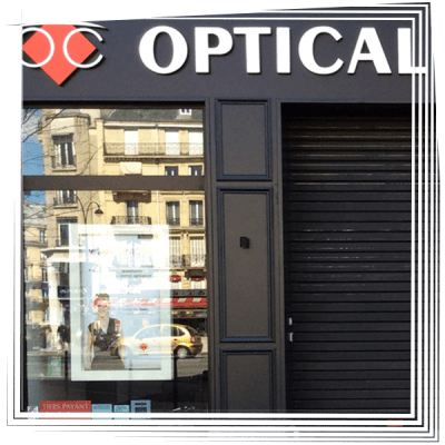 Façade d'un magasin d'optique avec une grande enseigne OPTIQUE et une vitrine réfléchissante.