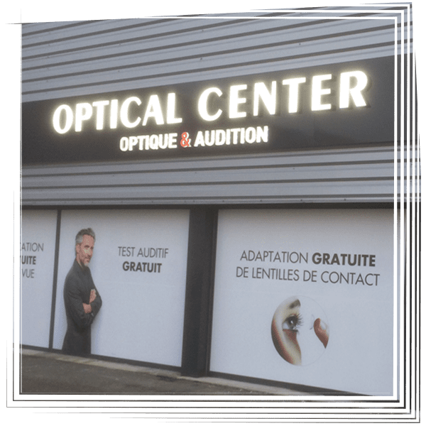 Enseigne de façade d'un centre d'optique avec inscription en français : opticien et audioprothésiste.