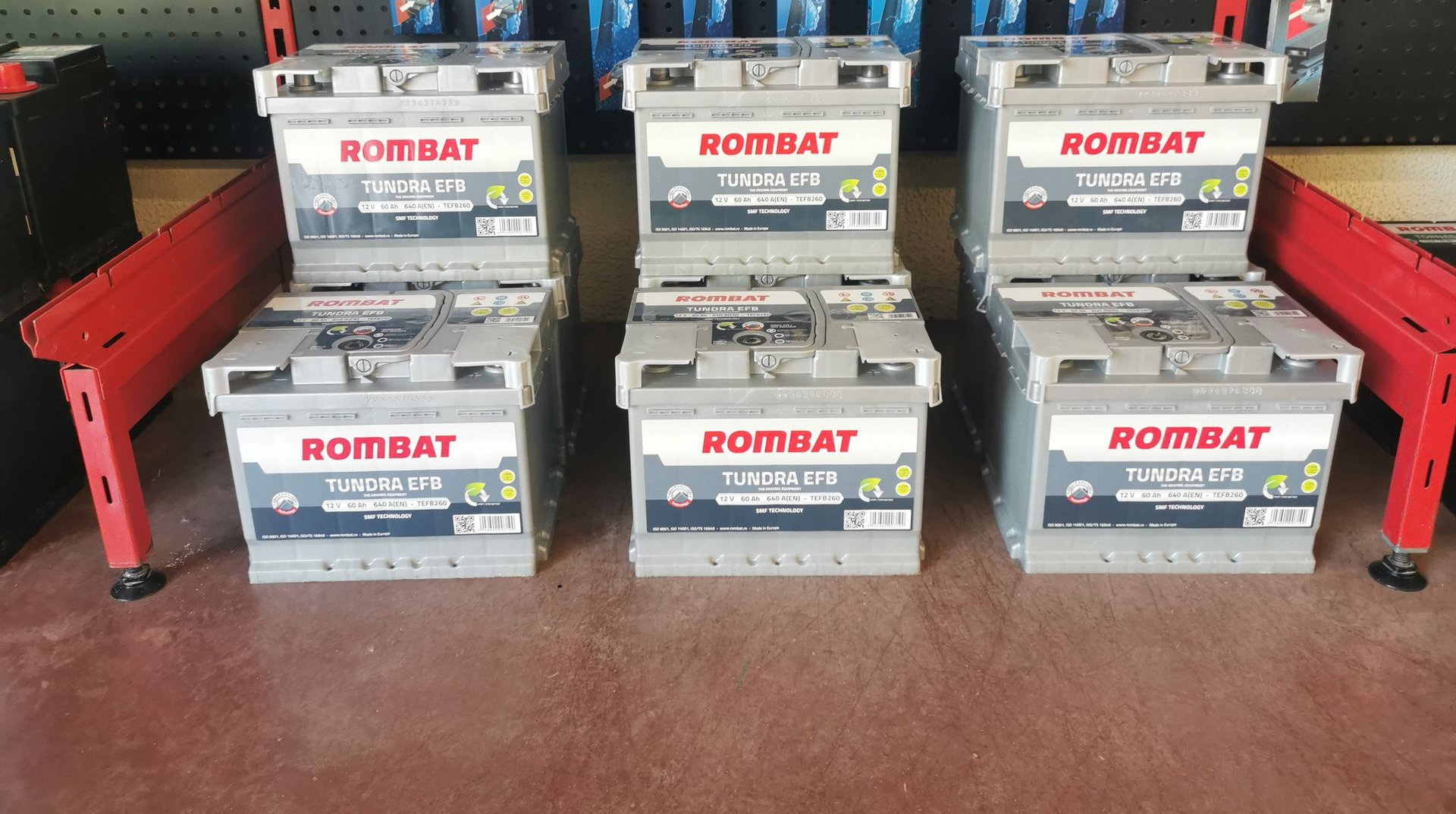 Six batteries de voiture empilées ; de marque Rombat, dans un magasin.