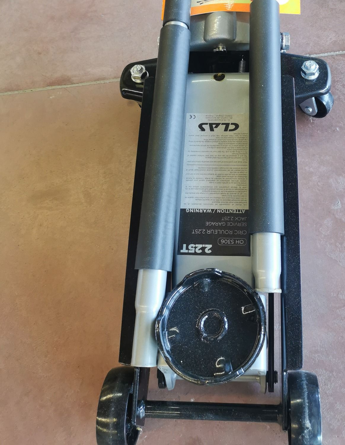 Cric hydraulique noir à deux poignées et à roue. Étiquette de prix jaune apposée.