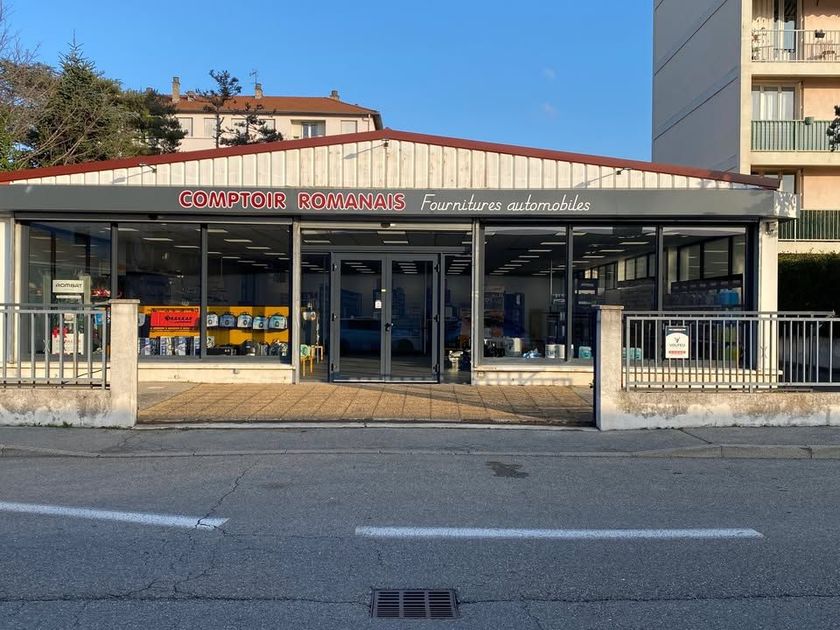 Vers page Romans-sur-Isère Façade du magasin avec vitrines, toiture métallique grise et enseigne.