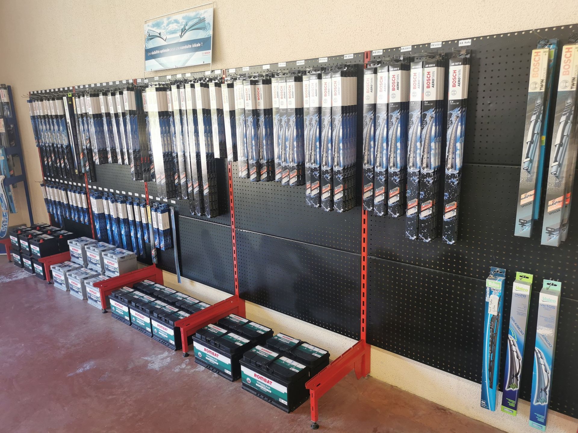 Un étalage d'essuie-glaces et de batteries de voiture à vendre dans un magasin.