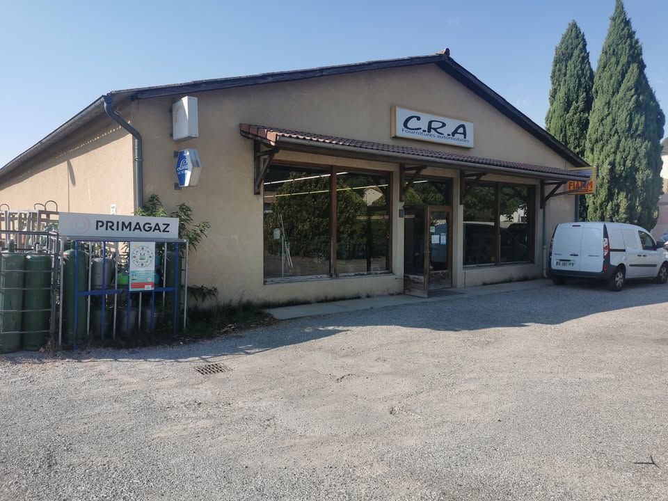 Vers page Crest Un bâtiment beige avec un panneau CRA, des bouteilles de gaz à gauche et une camionnette.