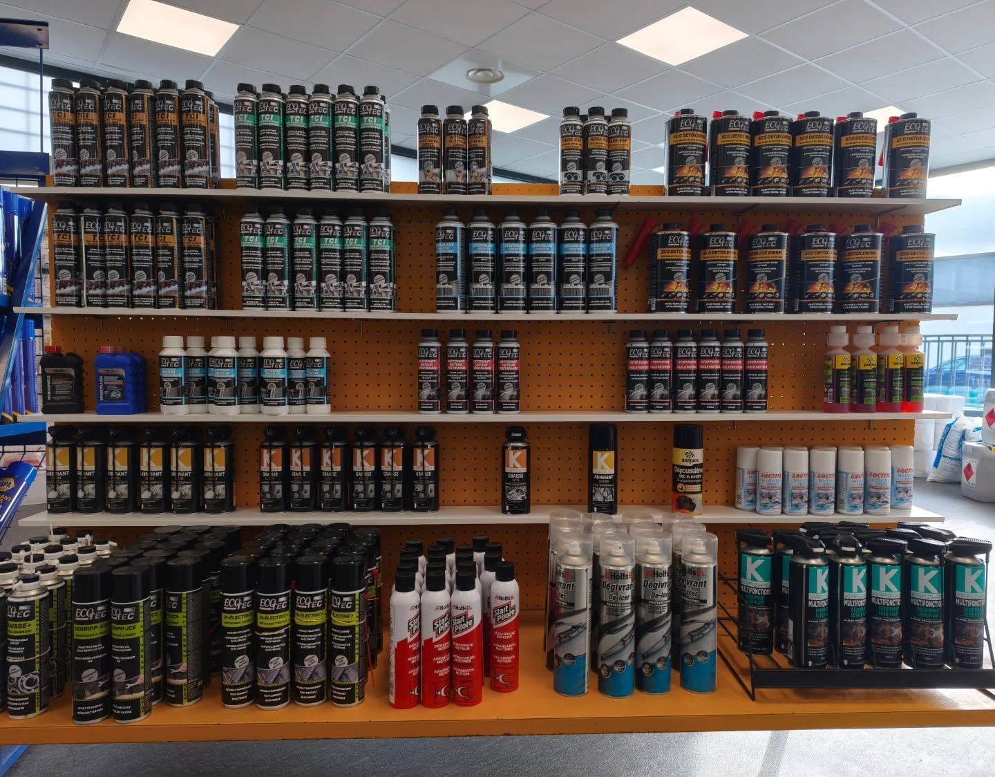 Des étagères remplies de diverses bombes aérosols de produits automobiles dans un magasin.