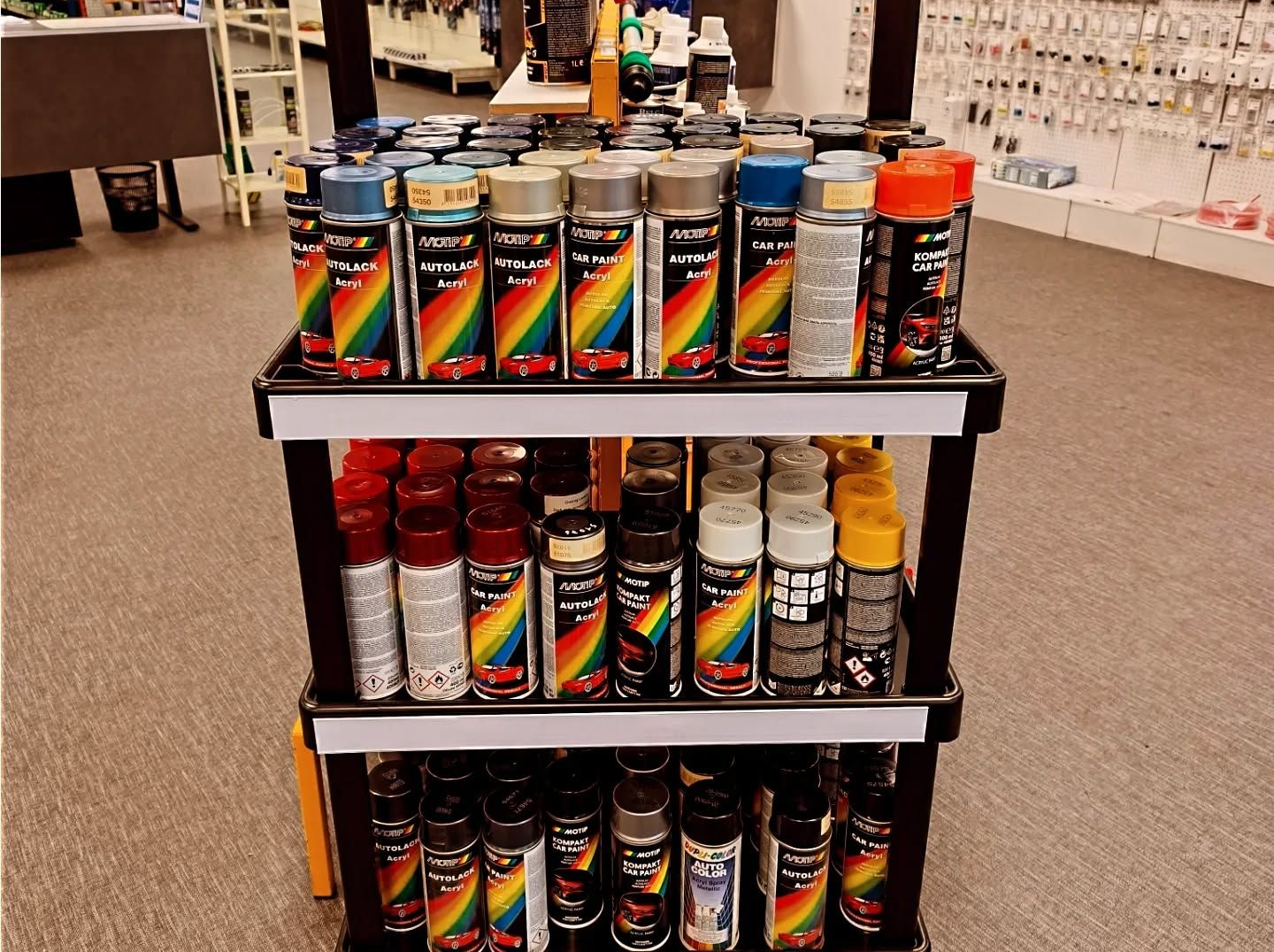 Présentoir de bombes de peinture de différentes couleurs, certaines arborant des motifs arc-en-ciel.