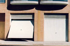 Un edificio con dos puertas de garaje que están abiertas y cerradas.