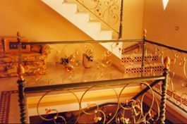 Una escalera con barandilla de hierro forjado y barandilla de cristal.