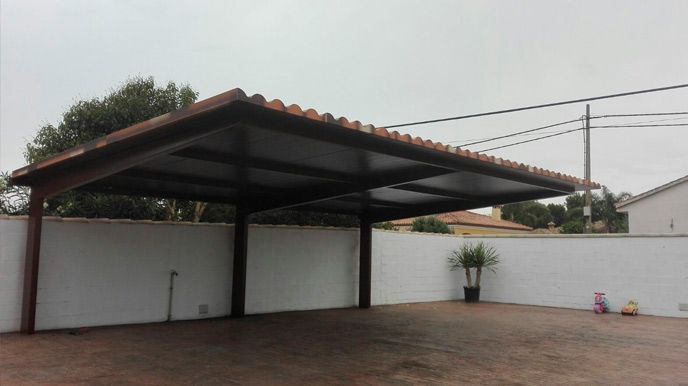 Una cochera con techo de tejas y una pared blanca