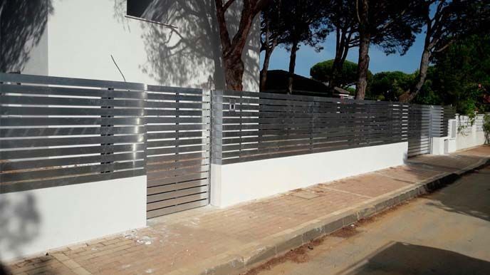 Una valla metálica rodea un edificio blanco al costado de la carretera.