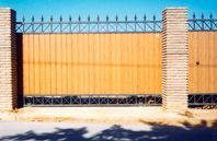 Una valla de madera con una valla de hierro forjado a su alrededor.