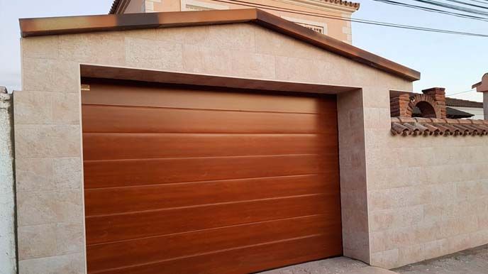 Una puerta de garaje de madera está junto a una pared de piedra.