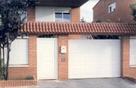 Una casa de ladrillo con una puerta de garaje blanca y un buzón.