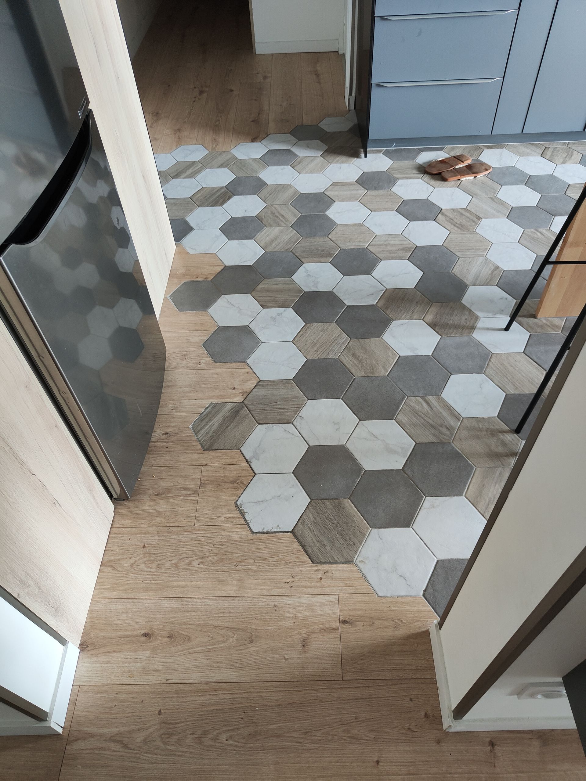 Sol carrelé en forme de tomettes en différentes teintes de gris