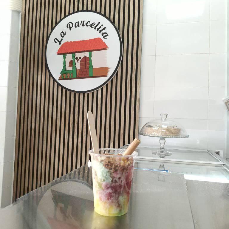 Vaso de postre con cuchara sobre un mostrador frente a un letrero de La Parcellia.