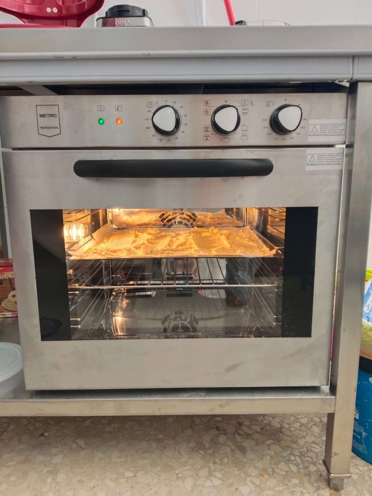 Horno empotrado de acero inoxidable con puerta de cristal, interior iluminado y tres mandos de control en la parte superior.