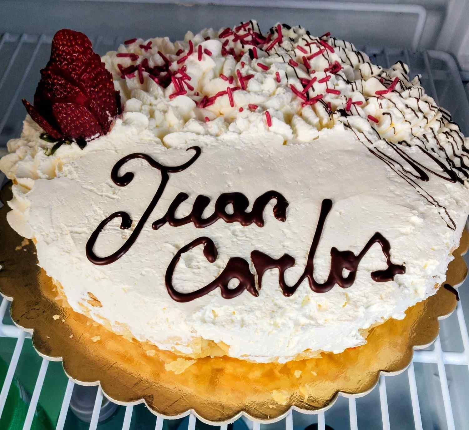 Pastel decorado con glaseado blanco, letras de chocolate que dicen 