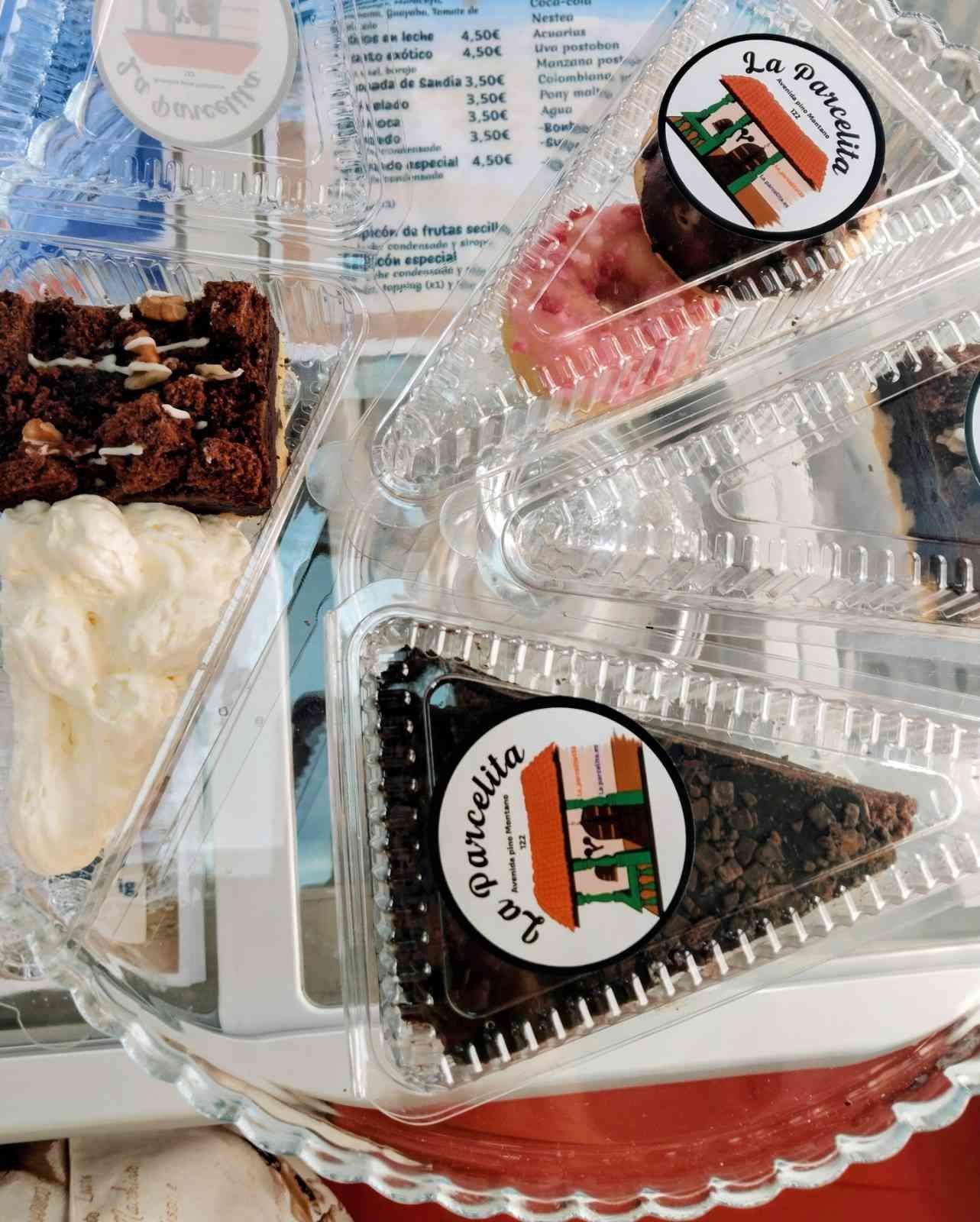 Surtido de pasteles y postres envasados ​​en una bandeja, con recipientes de plástico transparente y etiquetas.
