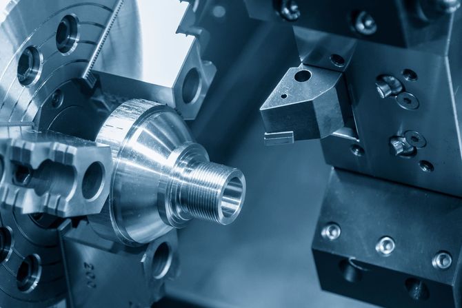 Nahaufnahme einer Metalldrehmaschine bei der Bearbeitung einer glänzenden Gewindewelle in einer Werkstatt