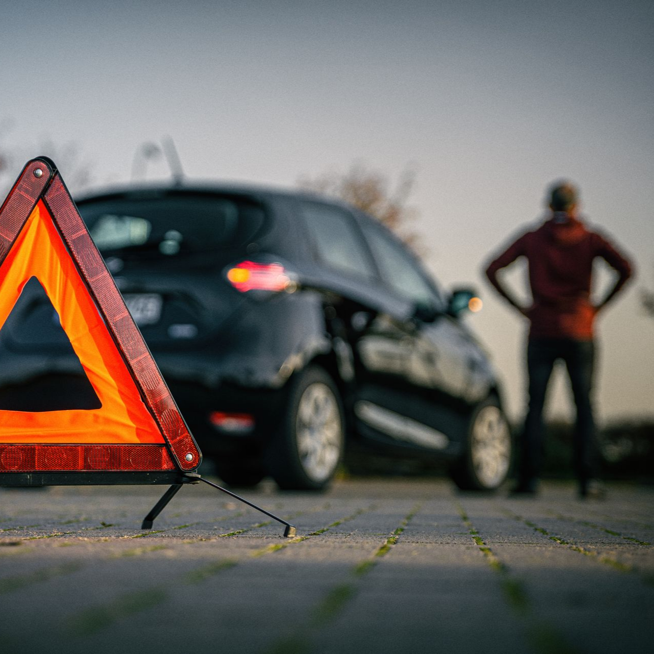 Automobiliste en panne sur la route avec un triangle de sécurité