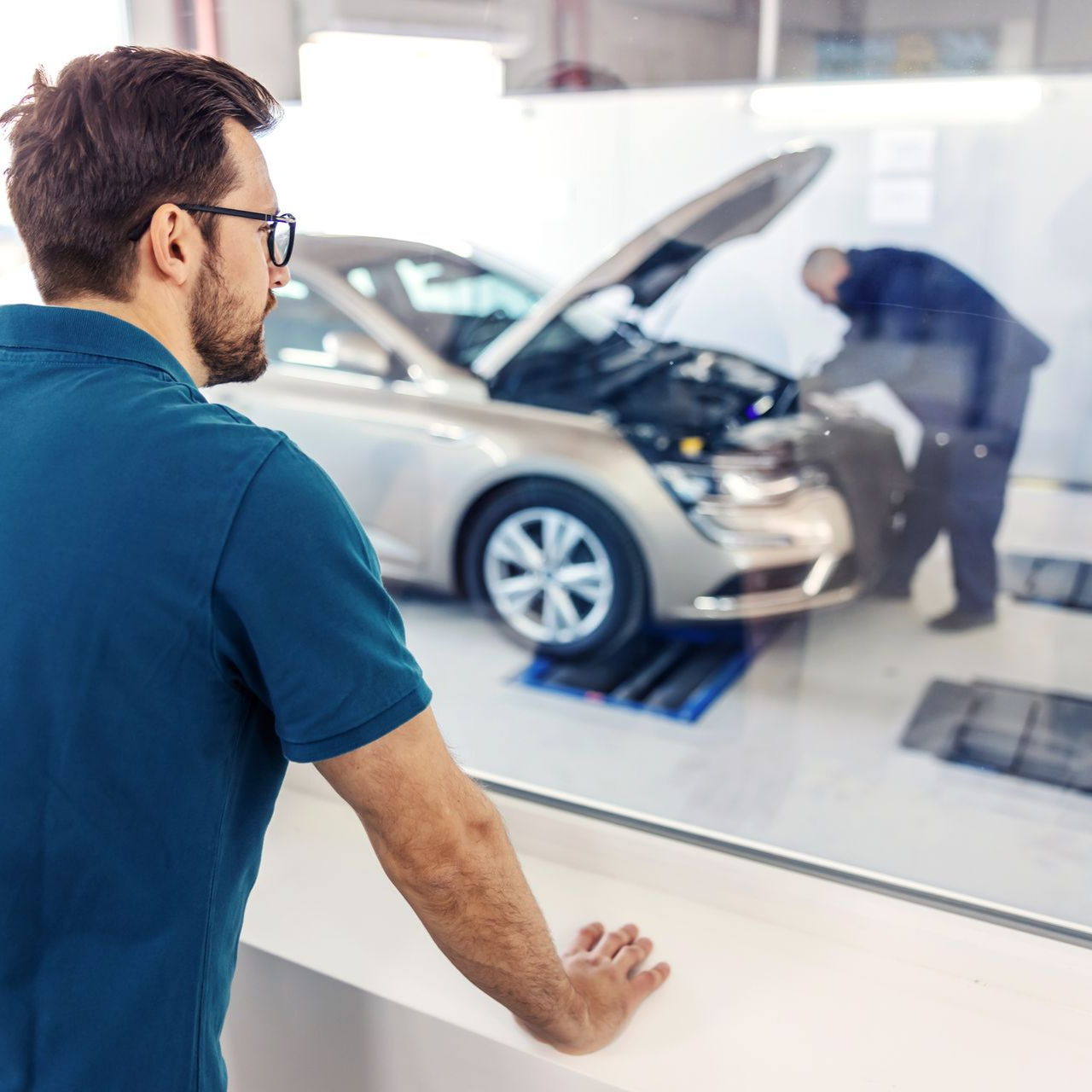 Un homme regardant un mécanicien contrôler sa voiture