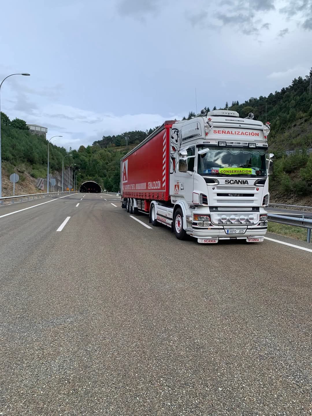 Un camión rojo y blanco circula por una autopista.