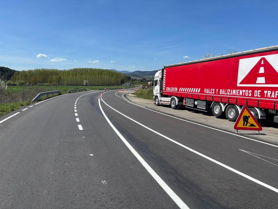 Un camión semirremolque rojo está estacionado al costado de una carretera.