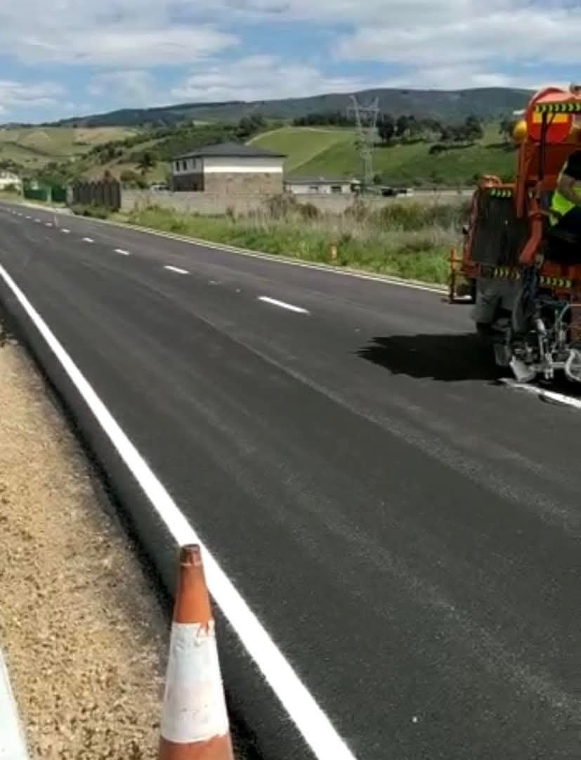 Un camión está pintando una línea blanca al costado de una carretera.