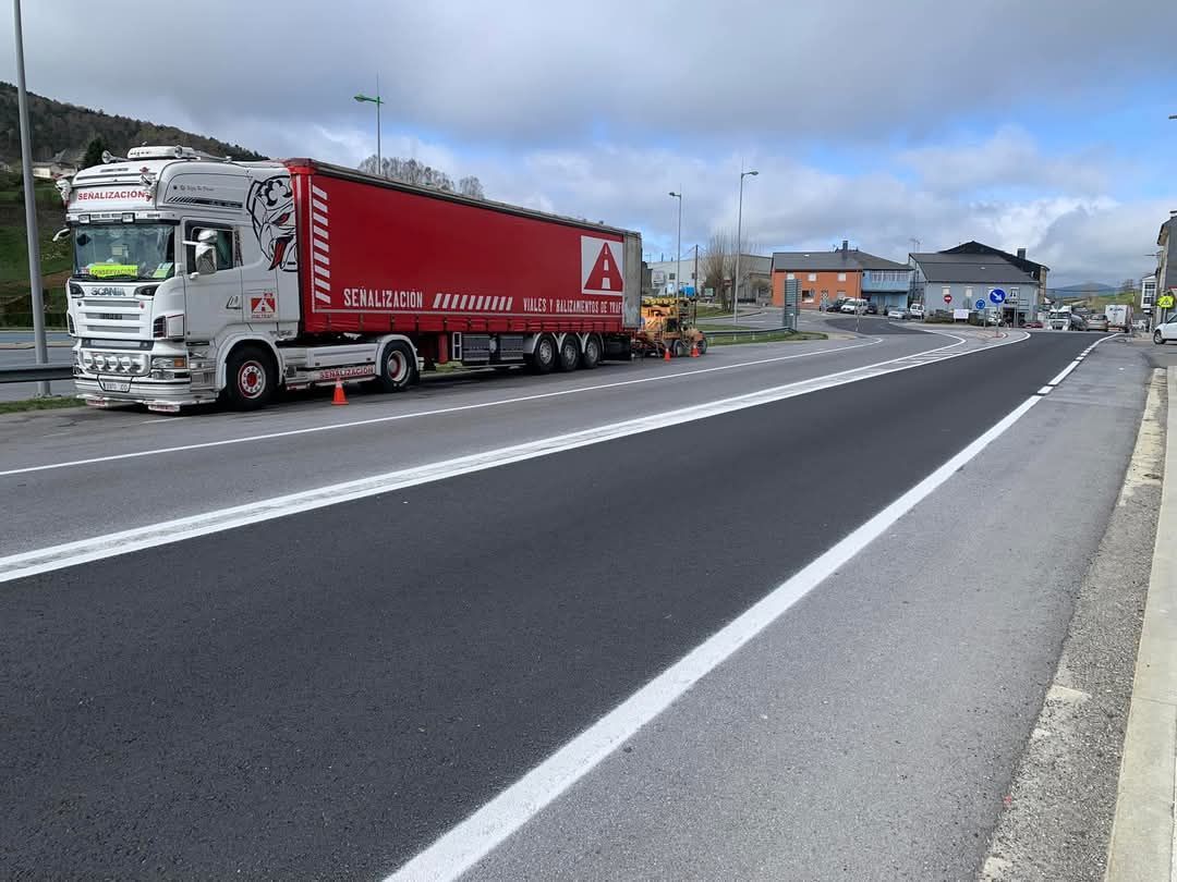 Un camión semirremolque rojo está estacionado al costado de la carretera.
