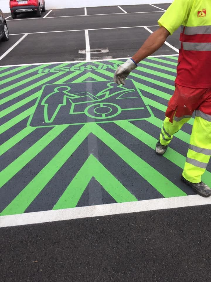 Un hombre está pintando un estacionamiento con rayas verdes y negras.