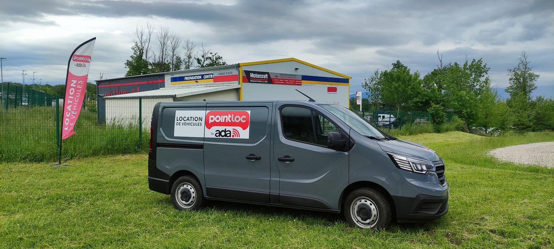Trafic gris garé sur une pelouse devant un garage auto
