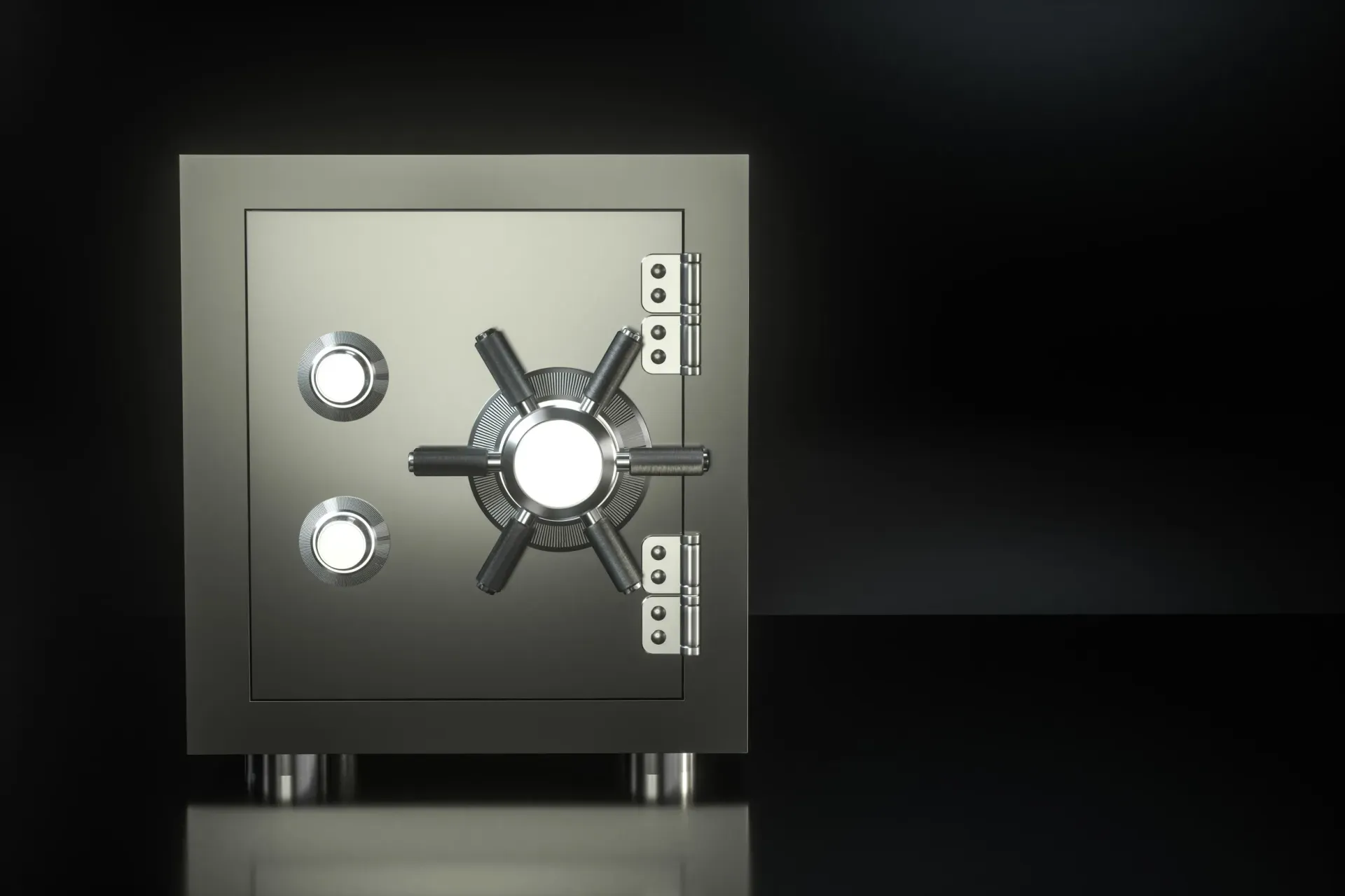 Una caja fuerte plateada brillante con un mecanismo de bloqueo sobre una superficie negra reflectante.