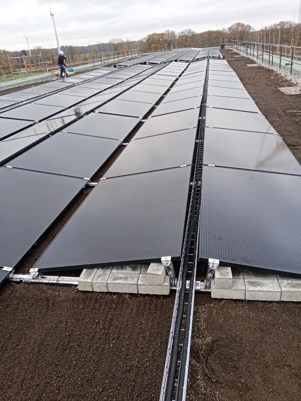 Auf einem Dach installierte Solarpaneele; im Hintergrund ein Arbeiter.