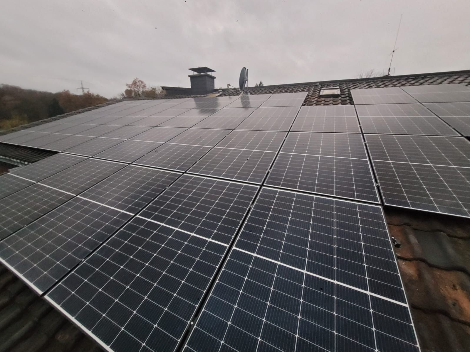 Auf einem Ziegeldach unter bedecktem Himmel wurden Solarpaneele installiert.