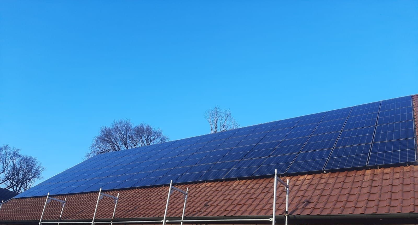 Solarpaneele auf einem roten Ziegeldach vor strahlend blauem Himmel.