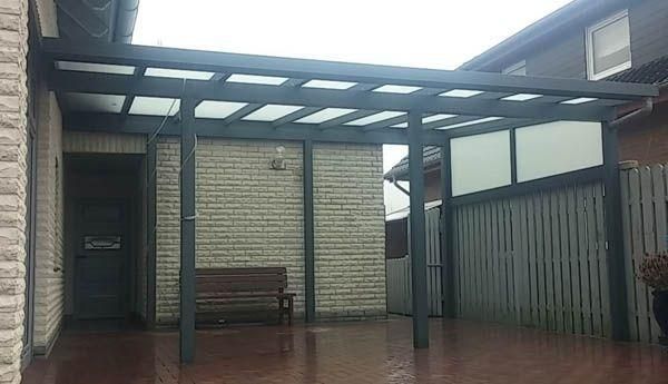 Ein an ein Haus angebauter Carport mit grauem Rahmen und lichtdurchlässigen Dachplatten.