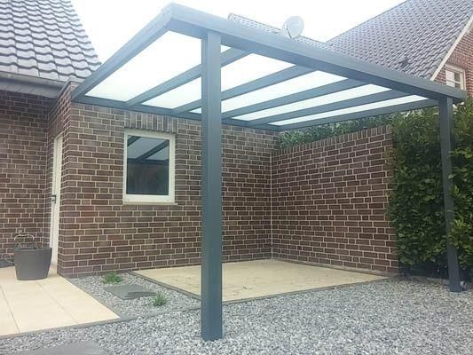Graue Pergola mit lichtdurchlässigem Dach über einer mit Ziegeln ummauerten Terrasse.