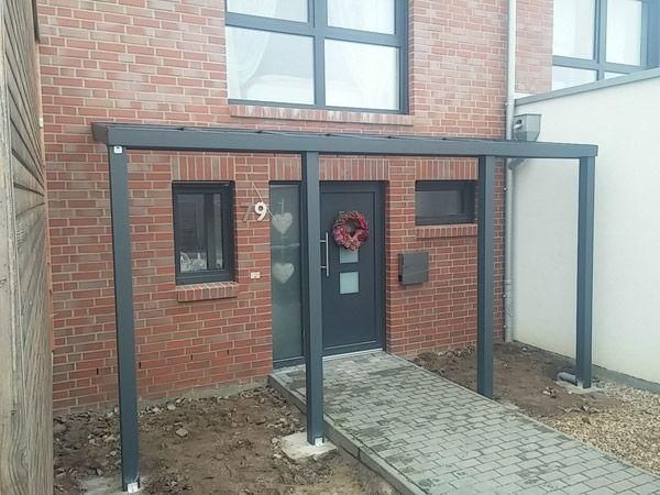 Ein Backsteinhaus mit einem Metallvordach über der Eingangstür und einem Backsteinweg.