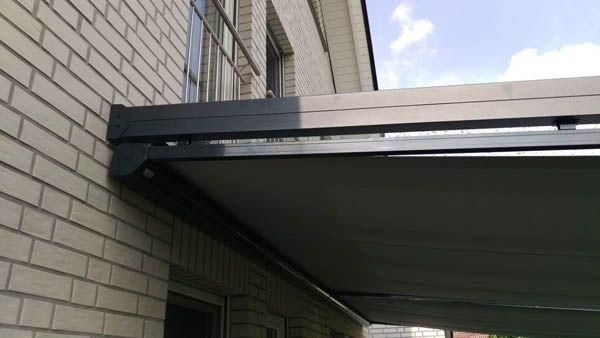 Dunkelgraue, einziehbare Markise an einem Backsteingebäude.