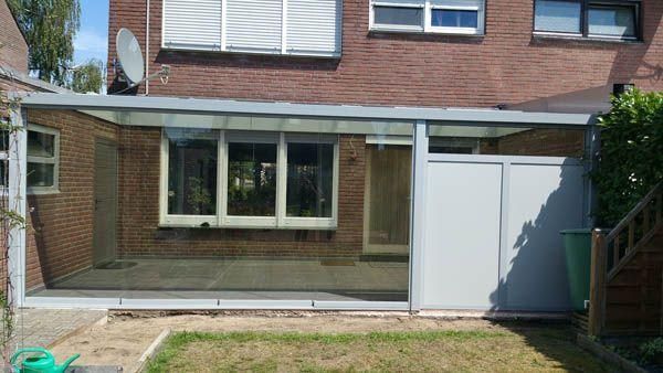 Terrasse mit transparentem Dach und grauem Abstellraum.