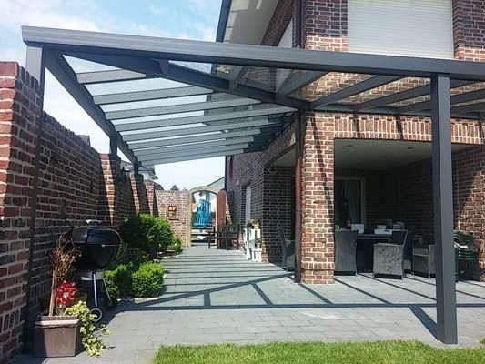 Terrasse mit Glasdachverlängerung, Backsteinmauern und Sitzgelegenheiten im Freien.