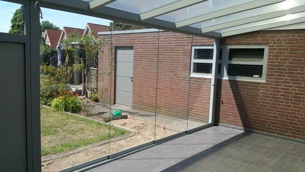 Verglaster Wintergarten mit Blick auf ein Backsteingebäude, Hinterhof mit Schuppen und Rasen.