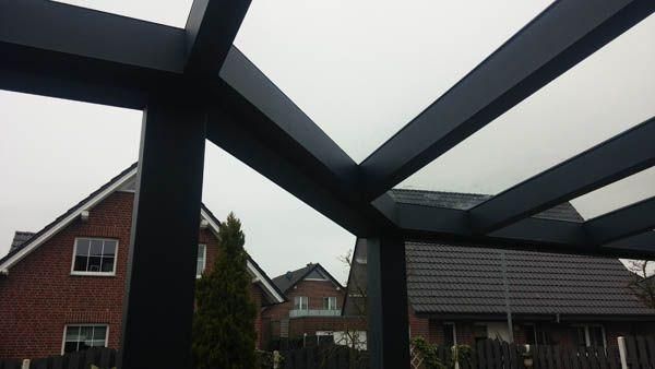 Schwarze Aluminiumpergola mit Blick auf Häuser an einem bewölkten Tag.