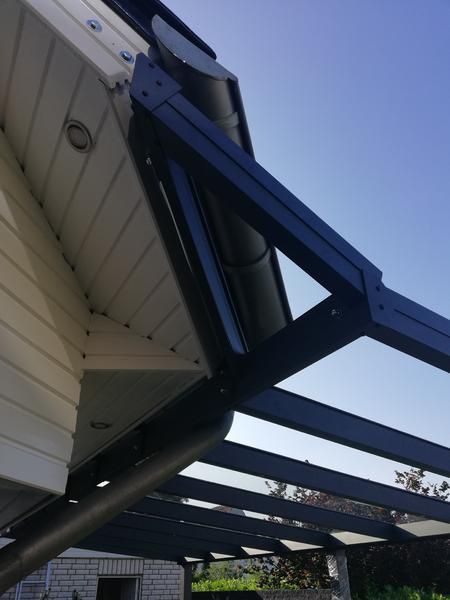 Schwarze und graue Markise an einem weißen Gebäude; klarer Himmel im Hintergrund.
