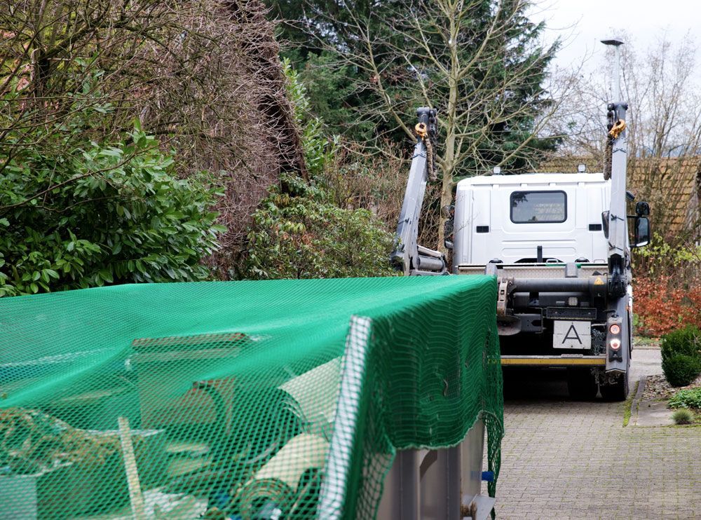 Ein weißer Lieferwagen, vollgepackt mit Umzugskartons und zwei verpackten Stühlen, steht auf einer Einfahrt.